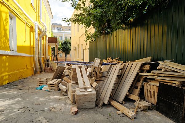 Wooden construction waste near fence and yellow wall debris for hauling in long beach ca